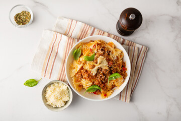 Top view of bolognese pasta with cheese in white bowl italian food on light table