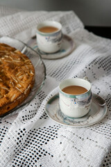 Breakfast or coffee break accompanied by homemade almond cake in a rustic, intimate and cozy atmosphere. Coffee served and ready to drink in cups crafted on an ornate table.