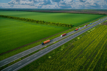 convoys with cargo. truck on the highway. asphalt road among green fields and beautiful clouds. cargo delivery and transportation concept