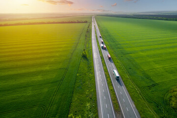 convoys with cargo. truck on the highway. asphalt road among green fields at sunset. cargo delivery and transportation concept