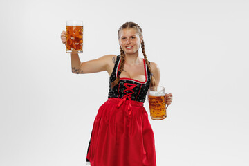 Adorable smiling woman, waitress wearing a traditional Bavarian or german dirndl holding big mug of beer isolated on white background. Holiday, event, oktoberfest,