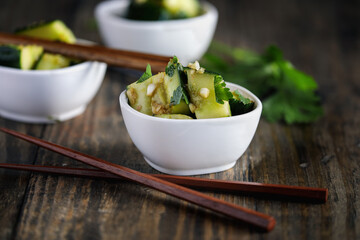 Chilled Pai Huang Gua, Chinese Smashed Cucumber Salad. Made with garlic, ginger, sesame oil, soy sauce and garnished with fresh cilantro leaves. Selective focus with blurred foreground and background.