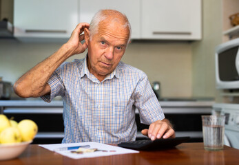 Man sitting at table at home calculating domestic finances and bills