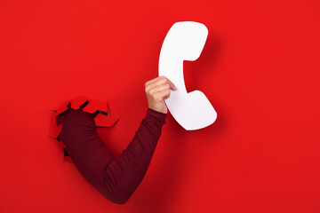 hand holding handset over red background, hotline concept