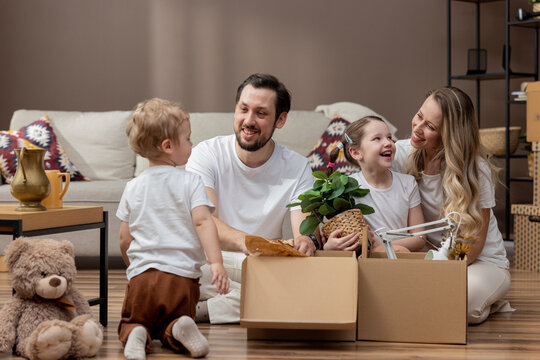 A family sits on the floor unpacking boxes in their new home after moving.