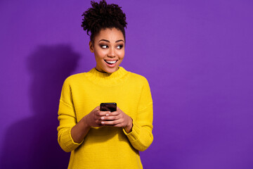 Photo of cheerful lady look interested empty space hold telephone blogging isolated on violet color...