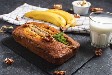Banana bread or cake on black stone table. Delicious homemade dessert, tasty snack or morning breakfast