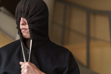 tense teenage guy in a black pulled-down hood covering the upper part of his face. Transitional age...