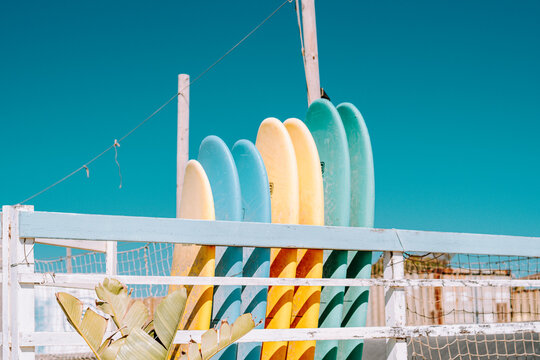 Set De Tablas De Surf De Diferentes Colores Apoyadas En Una Valla De Madera En La Playa