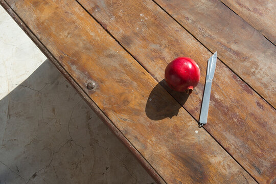 Red pomegranate on a wooden table. Summer fruits for breakfast. sunny still life with pomegranate