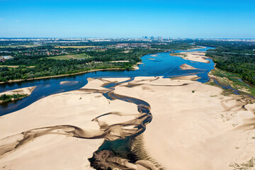 Low water level in Vistula river, effect of drought seen from the bird's eye perspective. City Warsaw in a distance. - obrazy, fototapety, plakaty