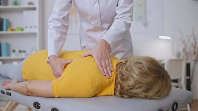 Close-up hands of doctor massaging female patient back, manual therapy treatment