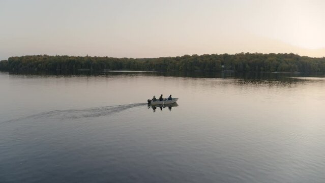 People in motorboat on lake at sunrise, North Bay, Ontario, Canada