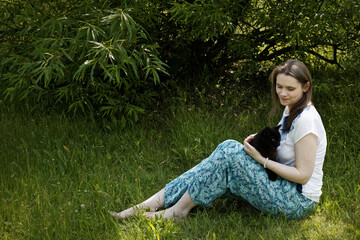 Woman with black cat relaxing on the ground in nature. Leisure time with pet outdoors.