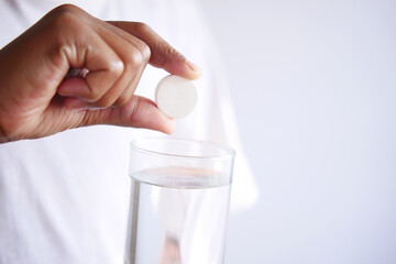 holding a Effervescent soluble tablet pills and glass of water 