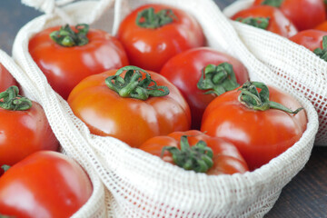 fresh tomato in a reusable shopping bag on table 