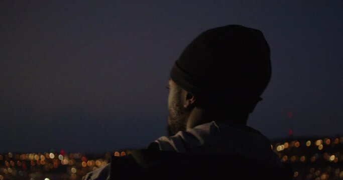 Young black man stopping during his run to admire city light during blue hour in the South of Germany.