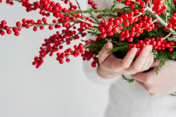Obraz na płótnie Canvas Woman hands holding ilex verticillata or winterberry for christmas decoration