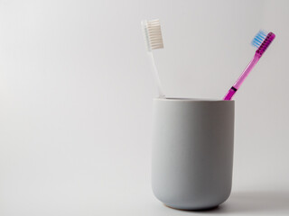 Toothbrushes in a glass with copy space on a white background