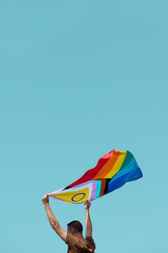 man waving a progress pride flag in the air