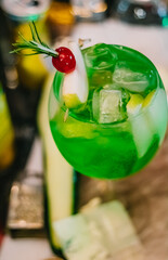 Special drink of green apple with cherry and Gin Tonic served in bar