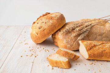 Fresh white wheat bread, round classic, ciabatta, french baguette, wheat ears and grains on white...