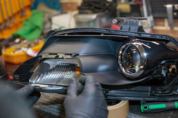 Car headlight in repair close-up. The car mechanic installs the lens in the headlight housing. The...