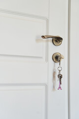 Part of white modern interior door with key in lock and metal handle. High quality photo