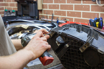 Car headlight in repair close-up. The car mechanic installs the lens in the headlight housing. The...