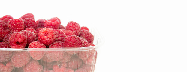 Fresh raspberries in a transparent container on a white isolated background, space for text