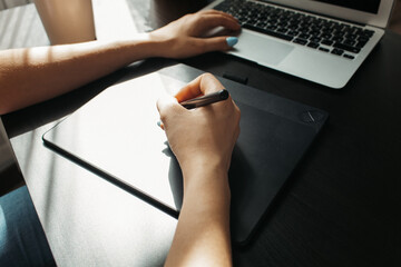 Close up of female graphic designer drawing sketches on graphic tablet