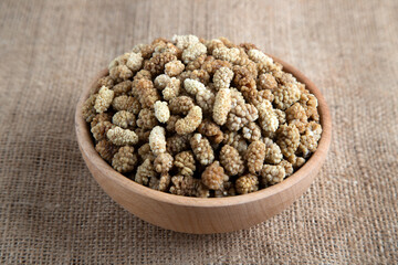 Bowl full of dried mulberry on a fabric background
