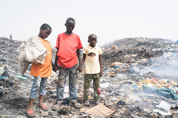 Three sad African streetboys make their living by recycling metals, plastic and other materials...