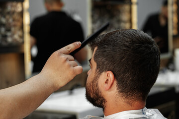 Male client getting haircut by hairdresser in barbershop