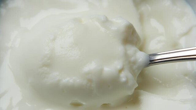 picking fresh yogurt with a spoon form a bowl 