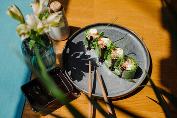 Fresh tasty sushi rolls with green leaves, salmon and juicy sauce on the served table at the sushi restaurant with beautiful contrast lightning