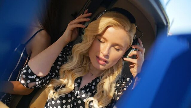 Young blonde girl wearing headphones sitting in a helicopter.Close-up.Slow Motion