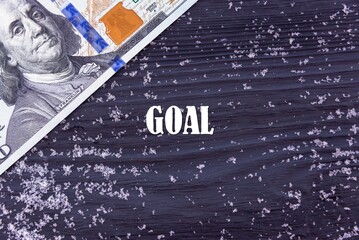 Fototapeta na wymiar GOAL - word (text) on a dark wooden background, money, dollars and snow. Business concept (copy space).