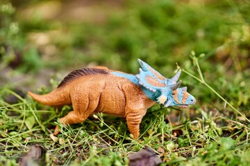 Closeup shot of a mini Mercuriceratops dinosaur toy figurine on green grass with blurred background