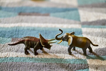 Closeup shot of a triceratops toy and an elephant toy on the carpet with a blurred background © Mirco Vacca/Wirestock Creators