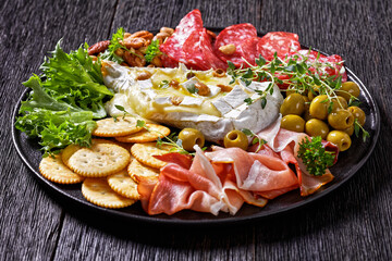 savory baked brie with crackers, salami, nuts, ham