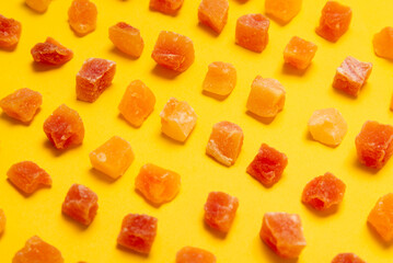 Lot of cubes of dried papaya on yellow background