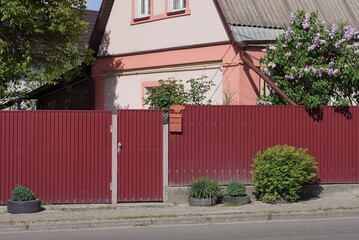 long red metal fence wall with closed iron door on rural street