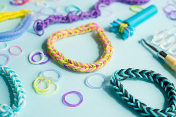 Closeup of making decorative bracelet with elastic bands on blue backround. Loom bracelets