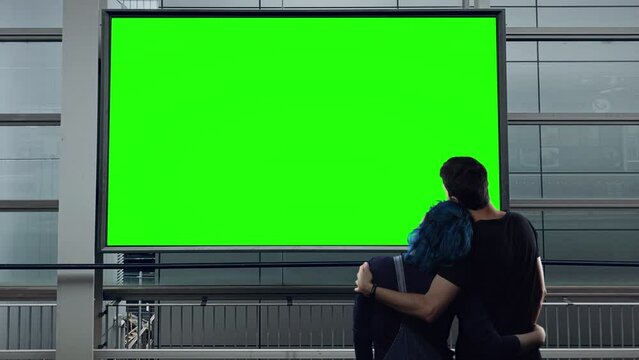 Embraced Couple Billboard Green Screen Exterior. Romantic couple standing in front of a green screen billboard outside building. Urban scene concept