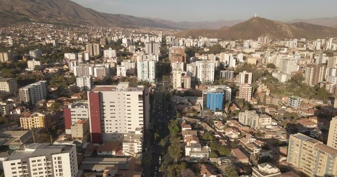 avenida en ciudad con edificios parques cerros drone