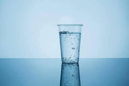Plastic cup of carbonated sparkling water on a blue background