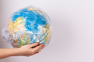 female hands hold a globe in their hands. earth model globe in a plastic bag, protecting the environment from debris.