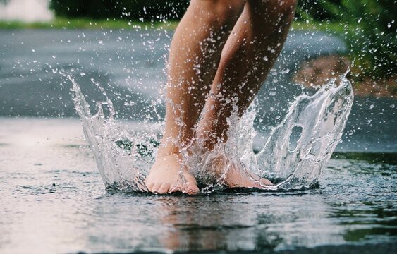 Closeup of the person's feet jumping in the puddle.