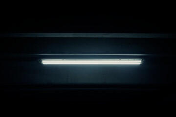 A scary ominous flickering neon light inside a basement. Problems with electricity, or something hiding in the shadows.
